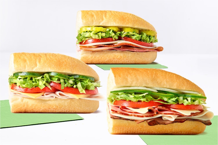 Ultimate, turkey, and Italian subs on green napkins.