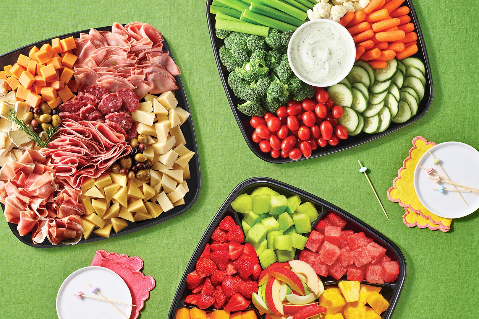 Display of Cheese Taster Platter Fruit Platter and Veggie Platter on green background