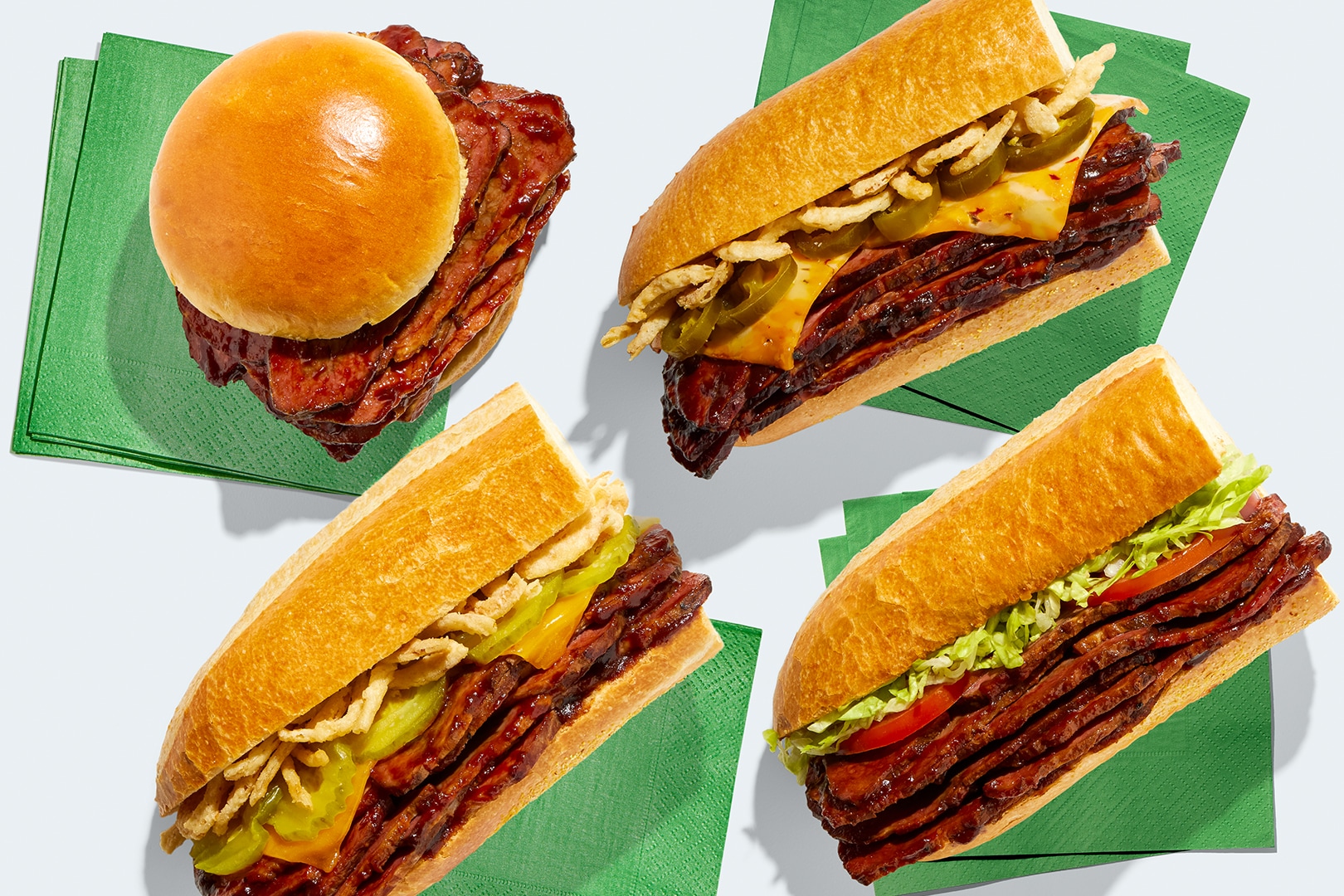 Brisket sandwich and subs on green napkins