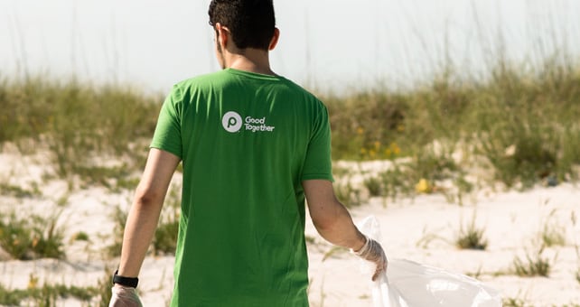 Publix employee picking up trash on a beach