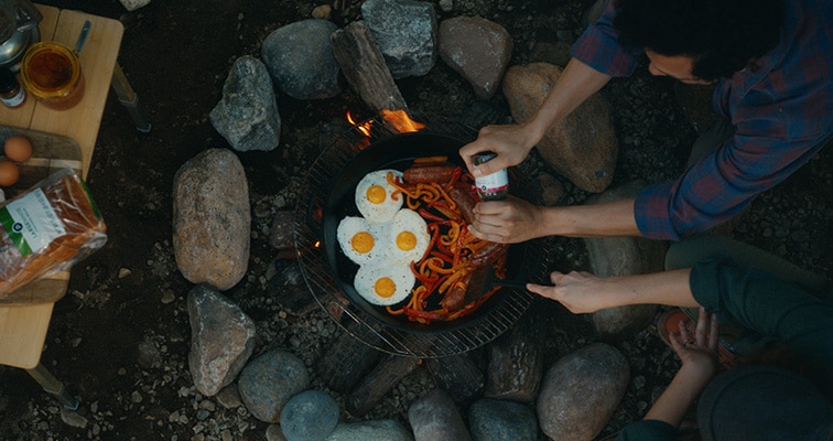 Food being cooked and shared around a campfire.