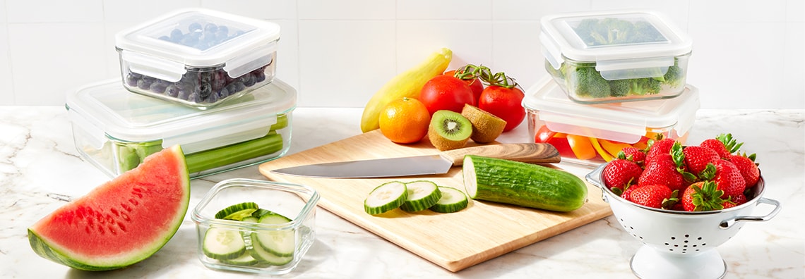 Fruits and vegetables being chopped up and stored in containers.