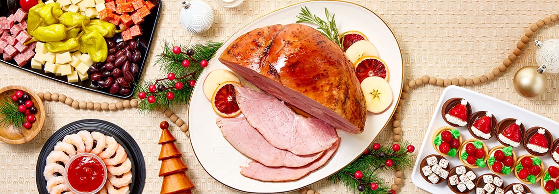 Holiday table with ham, cheese platters, shrimp cocktail, and festive desserts 