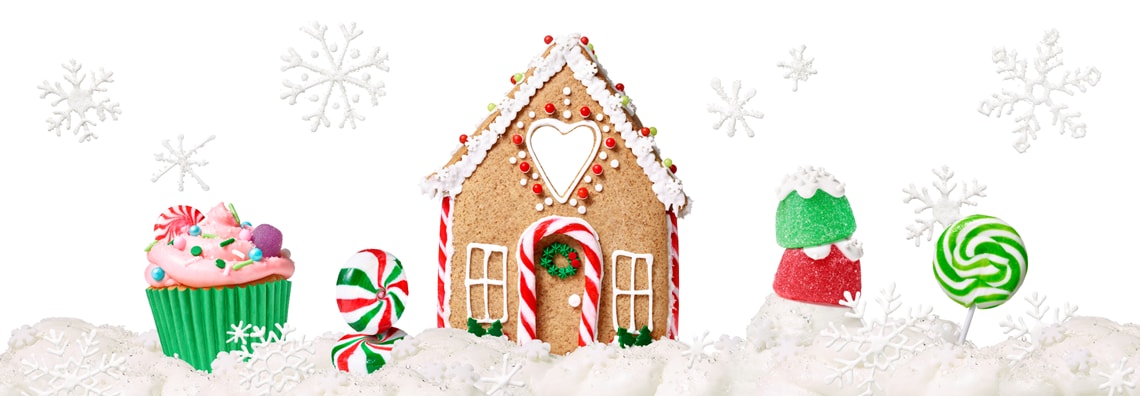 A gingerbread house surrounded by an oversized holiday cupcake, gumdrops, peppermint candies, and a large peppermint lollipop.