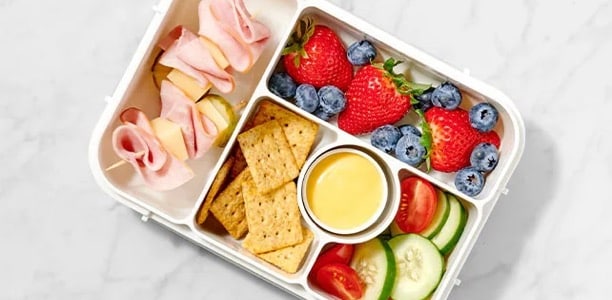bento box with ham, fruit, crackers, and veggies