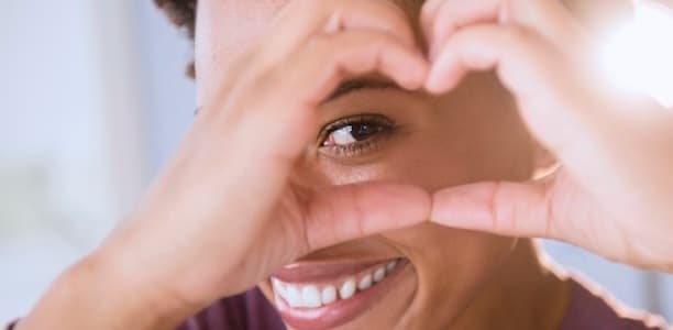 woman making a heart with her hands over her eye 