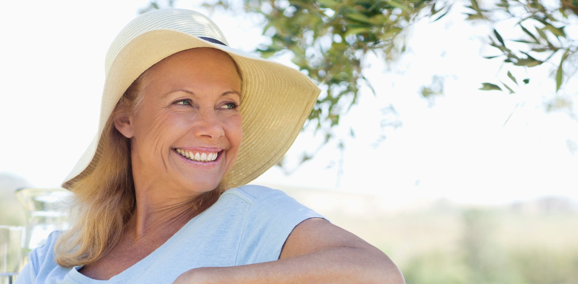 woman sitting outside wearing a wide brim hat 