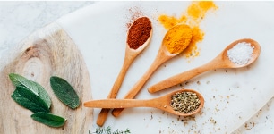 wooden spoons filled with various spices 