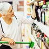 woman taking bottle of juice from a grocery shelf