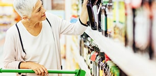 woman taking bottle of juice from a grocery shelf