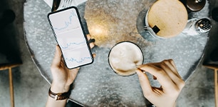 person holding cell phone and mixing coffee 