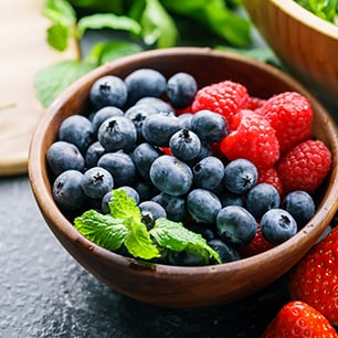 bowl of blueberries and raspberries with mint leaves