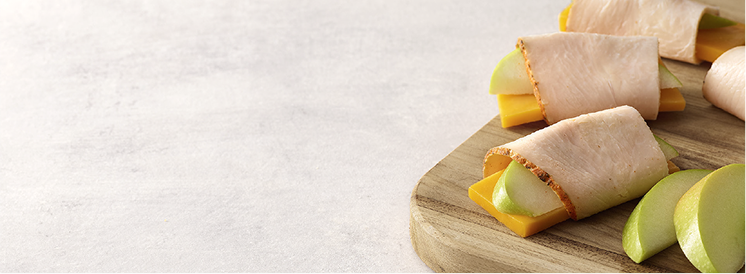 slice of turkey rolled around a piece of cheese and apple 