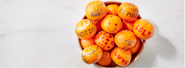 bowl of tangerines with phrases such as hugs,  be mine and cutie written on them 