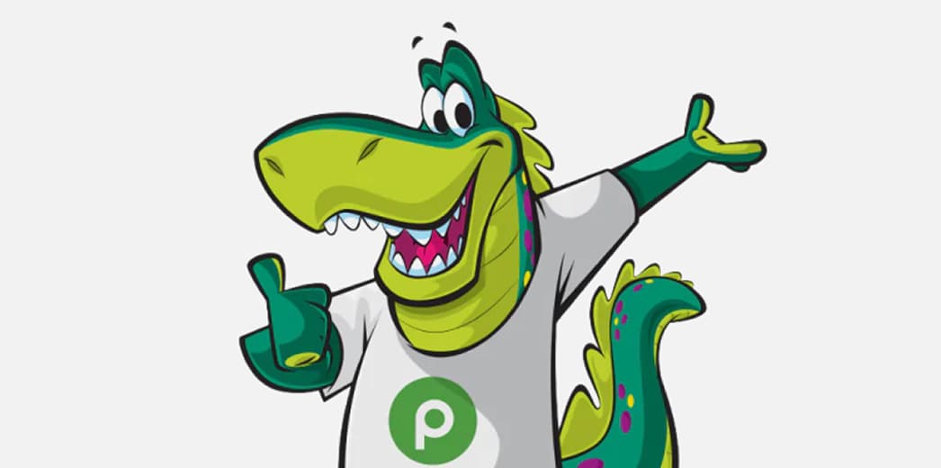 Plato the Publix dinosaur wearing a white t-shirt with the Publix logo and a big thumbs up 