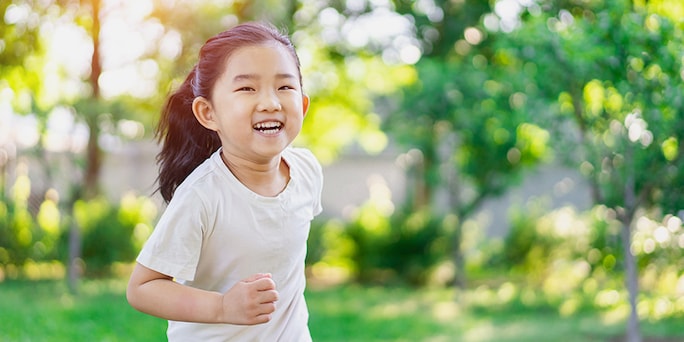 young girl smiling while running in a backyard