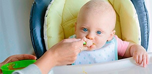 baby being fed in high chair