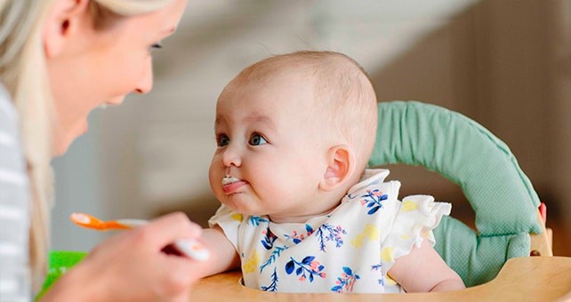 mom feeding baby in high chair