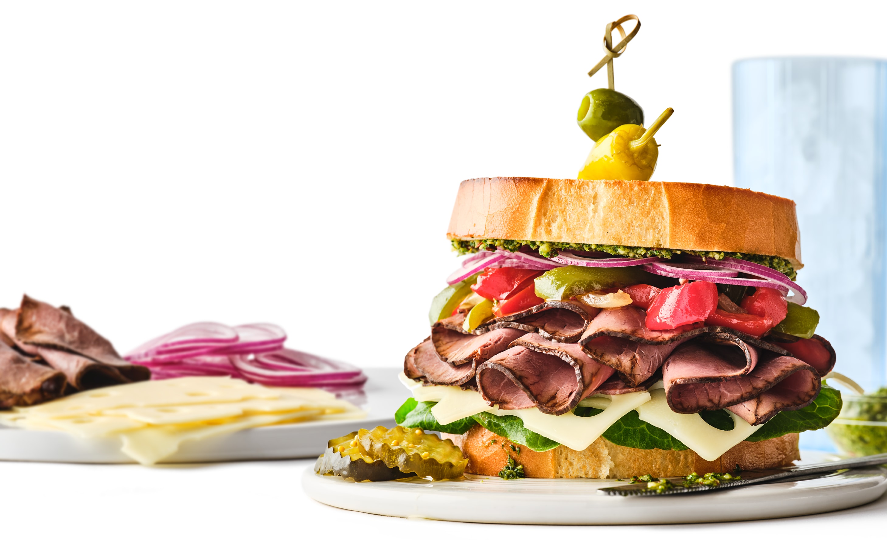 A stacked roast beef sandwich with cheese, lettuce, pickles, onions, and tomatoes, made with sliced meats and cheeses from the Publix Deli.