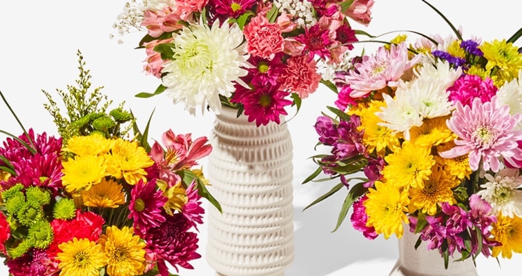 three colorful bouquets of flowers in vases 