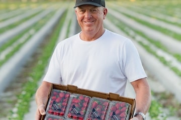 man holding a flat of strawberries 