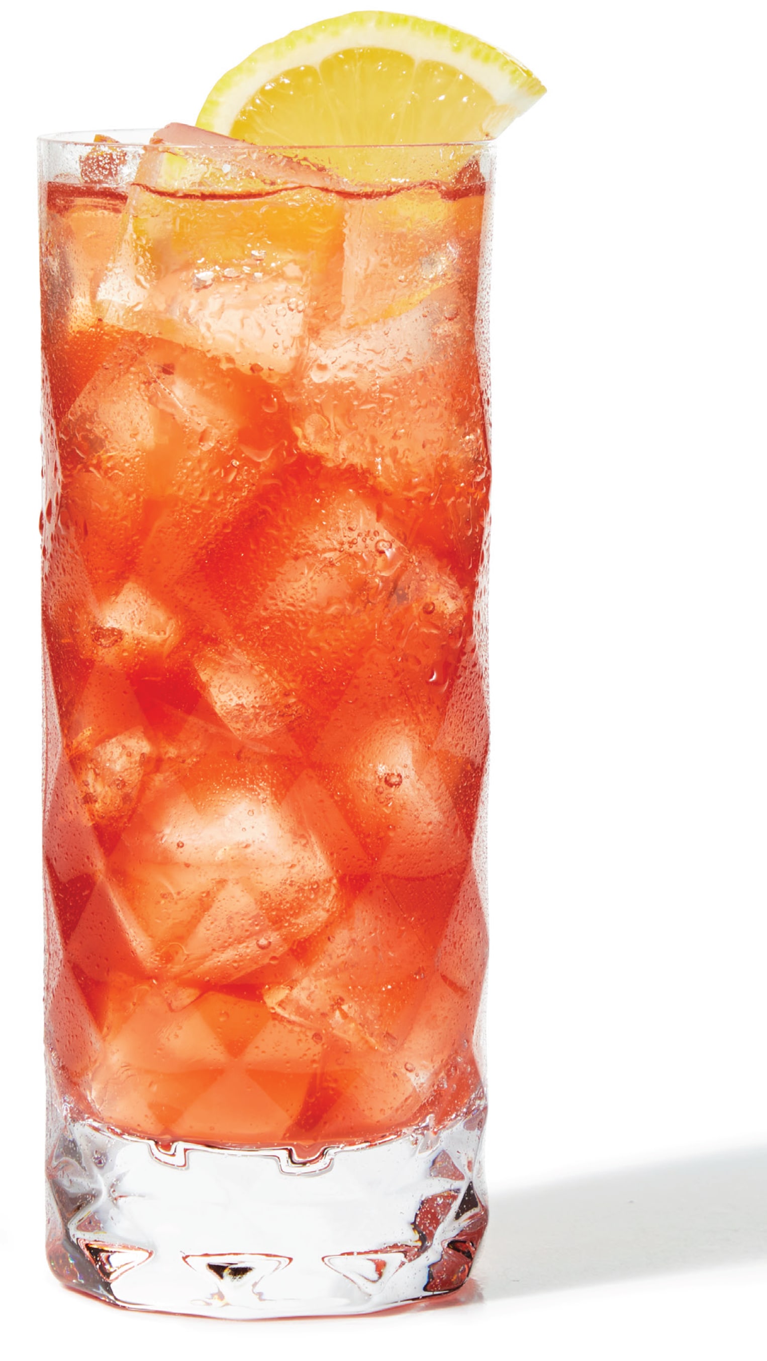 A cocktail served on ice in a high ball glass and garnished with a lemon wedge.