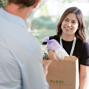 woman delivering Publix grocery bag to man's front door