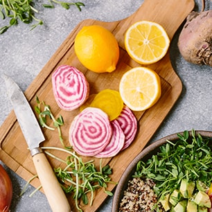 cutting board with lemons, onions, and herbs
