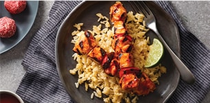 Barbecue chicken kabobs over cheesy rice with strawberry bites