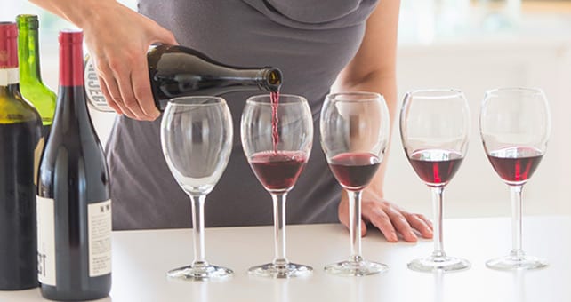 woman pouring wine into various glasses
