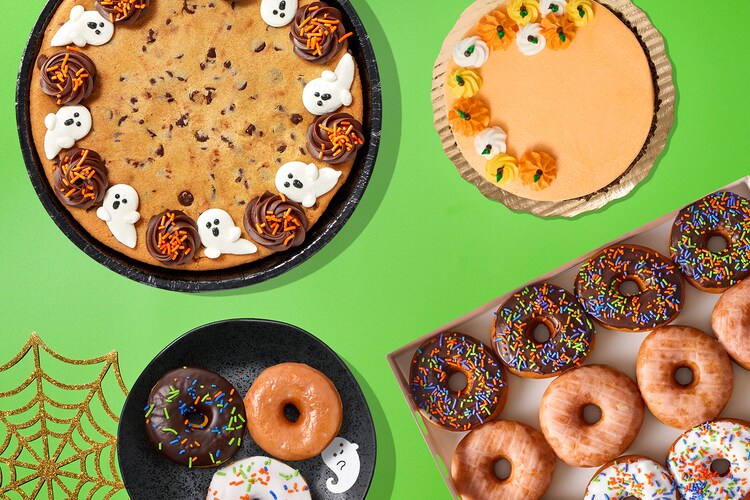 Halloween-themed cookie cake, mini cake, and donuts on a green surface.